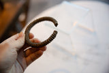 Antique African copper cuff bracelet with striped texture held in hand to show scale.