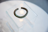 Angled view of the thick, oxidized copper cuff bracelet highlighting its open C-shape.