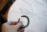 Antique African copper cuff bracelet held in hand, showing its scale and dark patina.