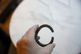 View of the antique copper cuff's circular shape and dark oxidized patina.