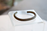 The finely striped surface and aged bronze patina on an antique African cuff bracelet.
