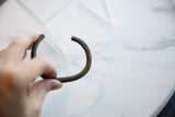 Curved profile of a striped African bronze cuff with an aged patina.