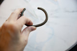Close view of the antique bronze cuff bracelet showing its open ends and patina.