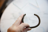Antique African bronze cuff bracelet held to display its open shape and scale.