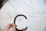Profile view of the antique bronze cuff highlighting its curved C-shape.
