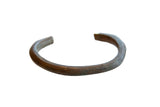 Antique African copper cuff bracelet with engraved striped details and a time-softened patina.