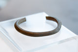 The aged patina and hand-etched striped details on an antique copper cuff bracelet.