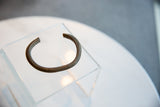 The C-shape profile of an antique copper cuff bracelet with a dark, textured patina.