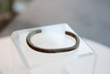 Side profile of the antique bronze cuff, detailing its aged surface and geometric etchings.
