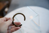 Antique African child's bronze cuff bracelet held in hand to illustrate its scale.