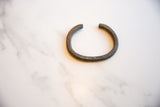 The handmade C-shape and textured, aged patina of a collectible African bronze cuff.