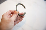 Hand holding the antique bronze cuff to show its handcrafted shape and scale.