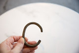 A hand holds the antique bronze cuff, showing its textured patina and scale.