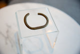 The open C-shape and aged patina of the handmade African bronze cuff bracelet.