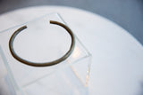 Antique African bronze cuff bracelet showing its curved form and striped texture.