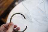 Antique striped bronze cuff bracelet held to show its scale and open C-shape.