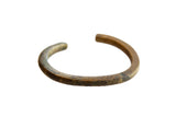 Antique African child's bronze cuff bracelet showing a weathered patina and faded incised detailing.