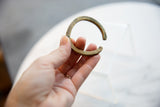 Antique African bronze cuff bracelet held to show its curved form and aged patina.