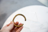 A hand holding the antique African bronze cuff bracelet to show its scale and aged patina.