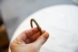A close view of the antique bronze cuff bracelet's faded, incised detailing and aged patina.