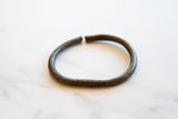 The open cuff and faded etched detailing of an antique African bronze bracelet.