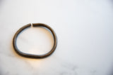 The antique bronze bracelet's hand-wrought texture and open cuff ends.