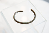 The open C-shape and dark, oxidized patina of an antique African bronze cuff.