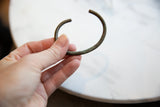 Antique oxidized bronze cuff bracelet held to show its scale and aged patina.