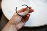 Antique bronze cuff bracelet held in hand to show its substantial form and scale.
