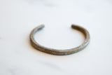 Antique aluminum cuff bracelet highlighting its simple open form and time-worn patina.