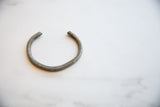 The simple, open C-shape of an antique African aluminum cuff with a matte patina.