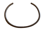 Vintage African bronze artifact with textured geometric detailing in an open circular form.
