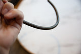 Hand-carved geometric detailing on the textured, curved surface of a vintage bronze artifact.