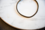 A vintage bronze artifact showing its simple ring shape and time-worn surface.