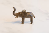 Side profile of a small African bronze elephant showing its rustic, handmade texture.