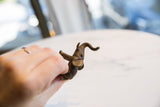 A vintage African bronze elephant figure with ears back, held to show its handmade texture.
