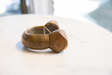 Profile view of a large copper cuff bracelet showing its geometric carvings and substantial form.