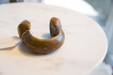 The heavy curve of a vintage African copper bracelet with hand-etched geometric details.