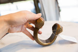 Holding the large African copper alloy cuff bracelet to demonstrate its scale and heft.