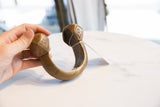 Profile view of the substantial African copper alloy cuff, showing its open design and aged patina.