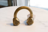 Profile view of an antique Tuareg cuff, showing its substantial bronze form and gold patina.
