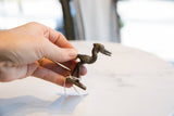Vintage dark bronze stork figurine held in hand to show scale.