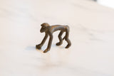 Side profile of a vintage bronze monkey highlights its smooth back and long limbs.