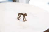 Side profile view of the vintage bronze monkey showing its smooth, arched back and aged patina.