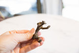 Collectible African bronze monkey figurine held to show its small scale and side profile.