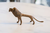 Aged bronze alloy African lion figurine in side profile, showing its textured body.