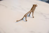 Aged bronze alloy texture and slender tail detail on the vintage African lion sculpture.