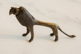 The stylized silhouette and textured, aged finish of a vintage African bronze lion.