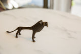 Side view of a vintage African bronze lion showing its stylized form and texture.