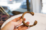 Hand holding antique African copper and bronze snake cuff, showcasing etched details and rich patina.